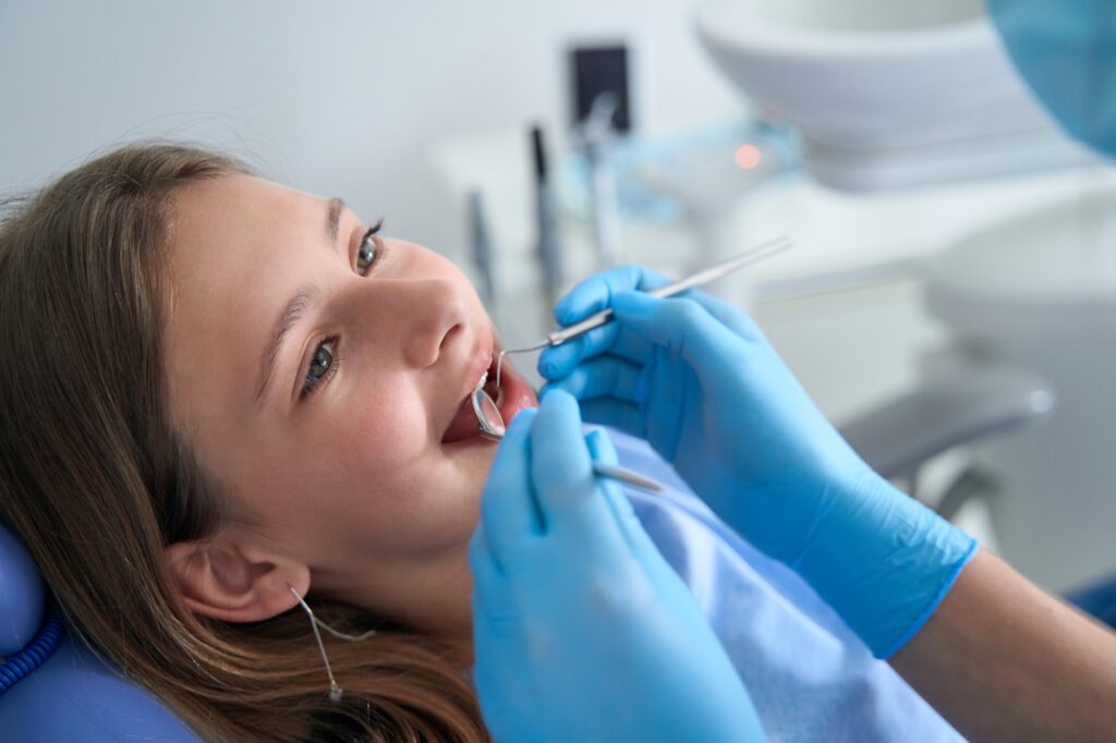 Doctor in nitrile gloves examining oral cavity of adolescent girl