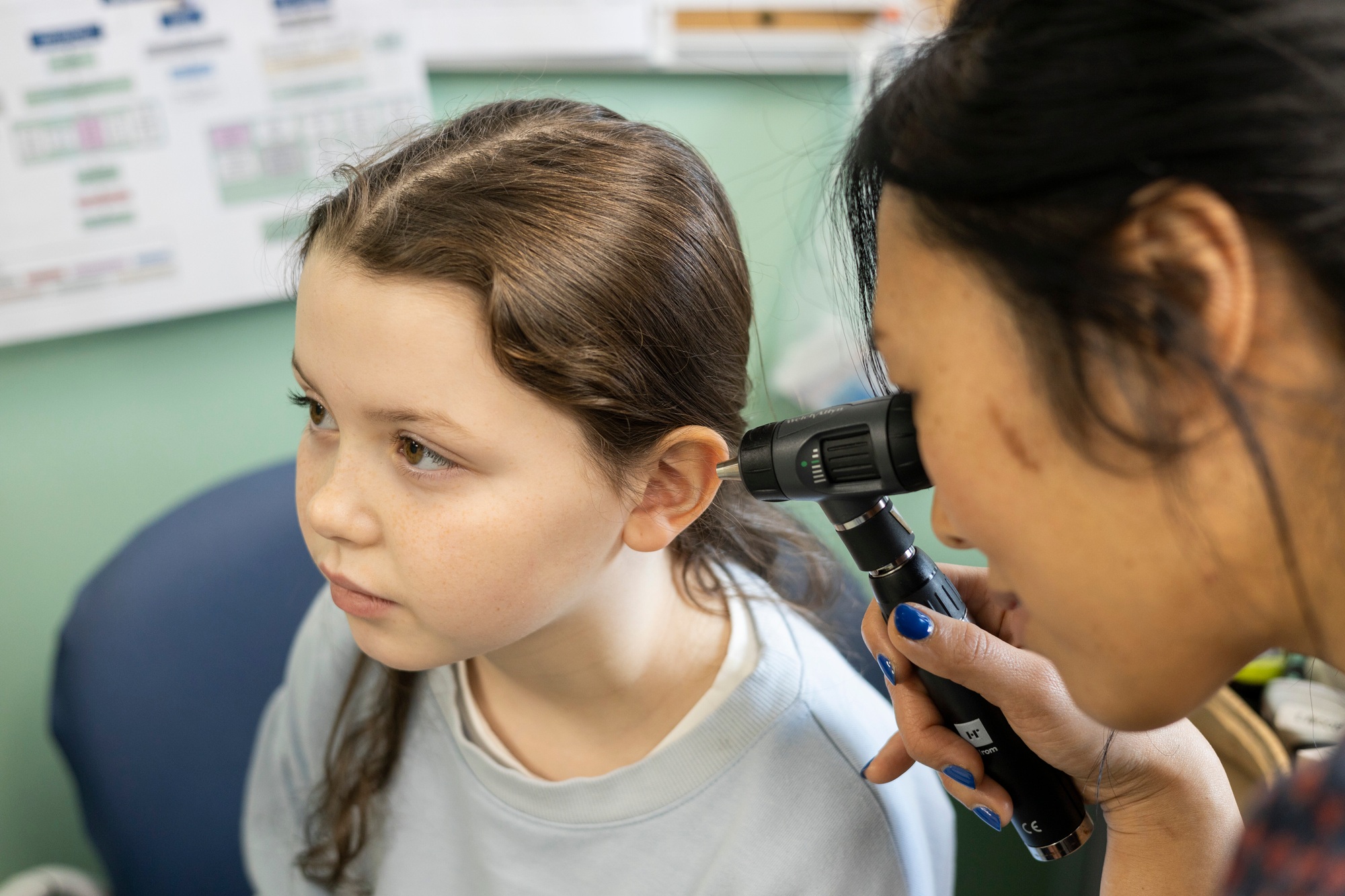 Doctor performing an ear examination on a young girl