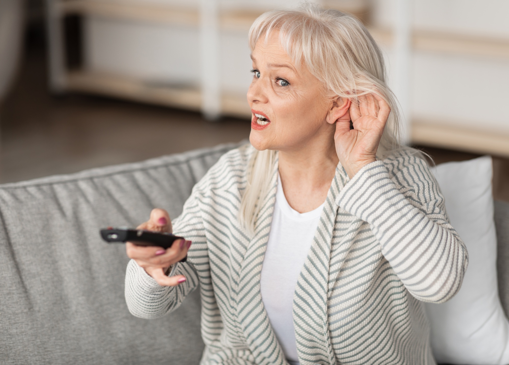 Hearing Problems. Mature woman watching television sitting on couch